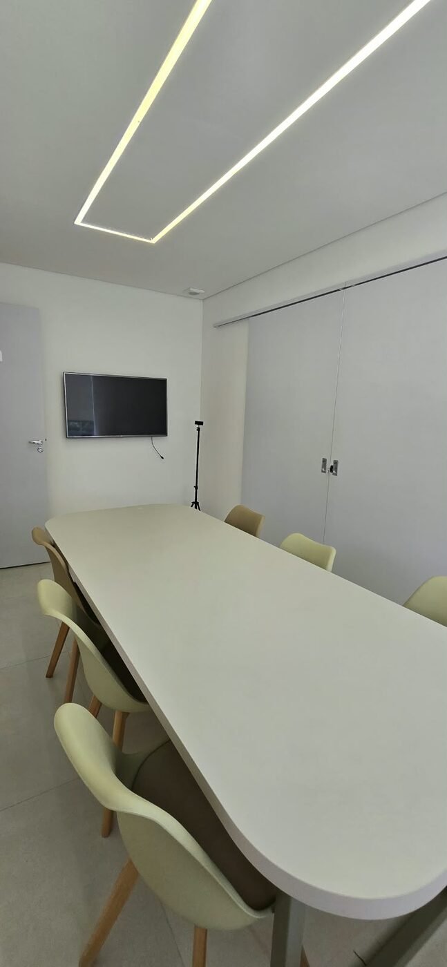 Sala de reunião do coworking Estetic Life, com mesa ampla e TV